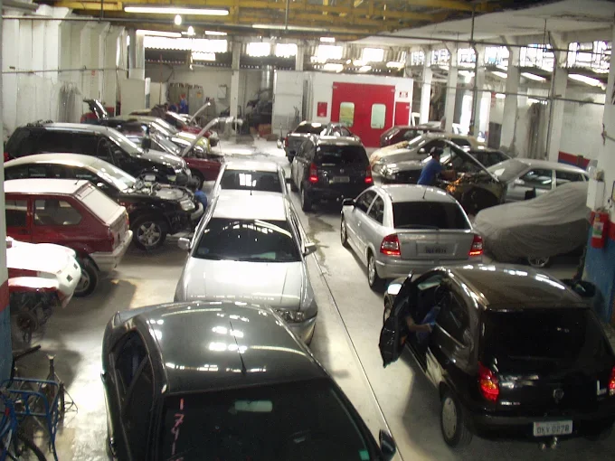 Área interna da oficina com veículos em funilaria, pintura e manutenção